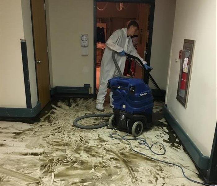 A water damaged floor with  SERVPRO employee cleaning it up