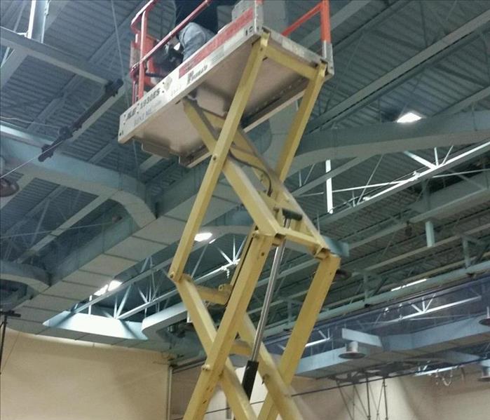 SERVPRO employee using a scissor lift to clean a commercial HVAC duct system