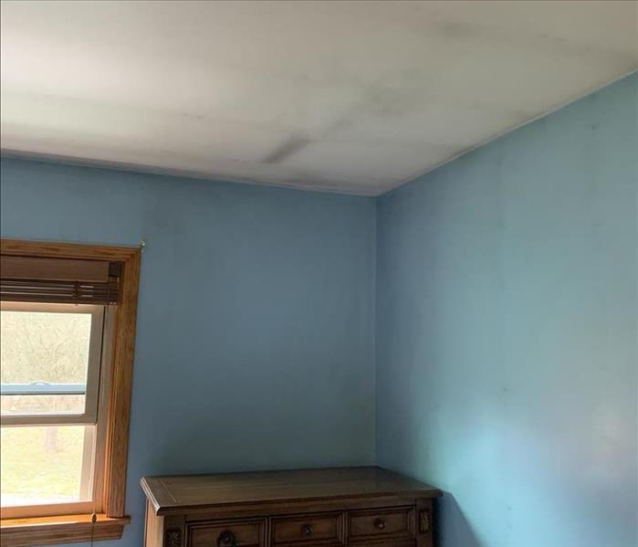 A blue painted room with soot damaged walls and ceiling from long-term candle use
