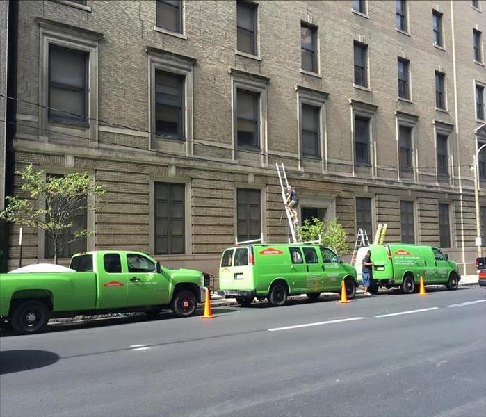 SERVPRO trucks parked next to a tall commercial building where we were working