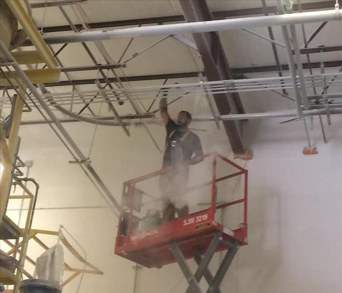 A SERVPRO employees in a scissor lift cleaning a high ceiling